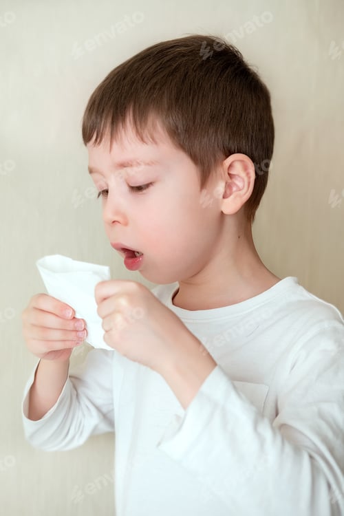 Preview: boy coughs, covering mouth with tissue. sick boy on a white background