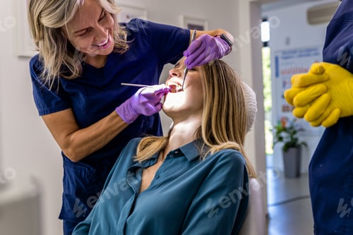 Preview: Female dentist with assistant working in dental clinic examining patient teeth.