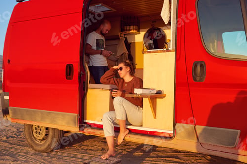 Preview: woman sitting in the camper trailer relaxed looking at the sunset over the horizon