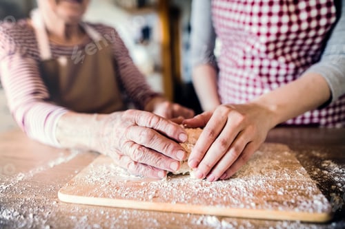 Preview: An elderly grandmother with an adult granddaughter at home, baking.