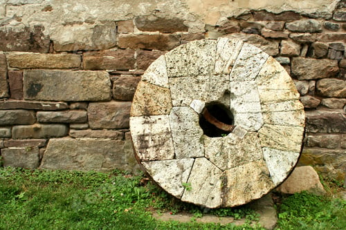 Preview: Old millstone leaning on a wall