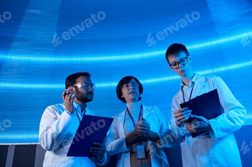 Preview: multiethnic scientists with clipboards working on futuristic technologies in science center