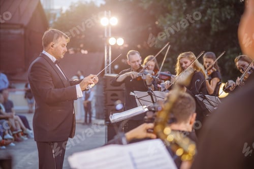 Preview: Male conductor directing orchestra performance on the street