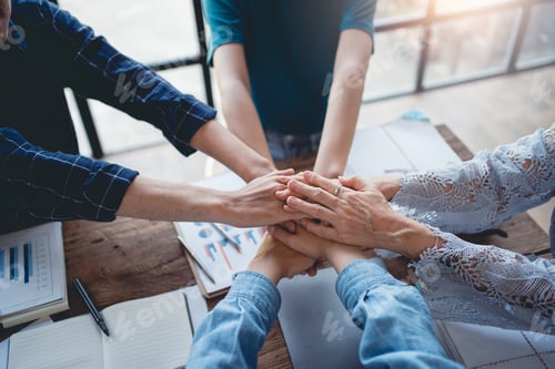Preview: Group of businesspeople putting their hands together to work together on new projects to see and dem