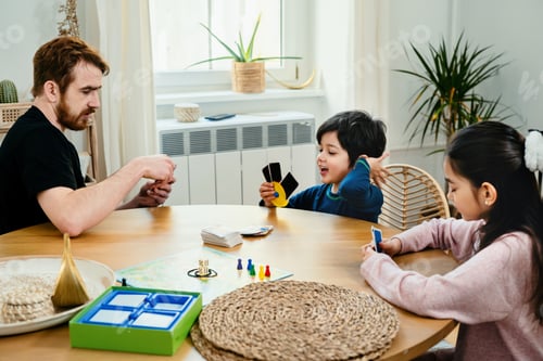 Preview: Father and kids playing with cards at the table