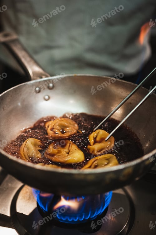 Preview: Chef cooking tortelloni with wine sauce on a hot pan. Authentic italian restaurant.