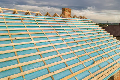 Preview: Aerial view of a brick house with wooden roof frame under construction.