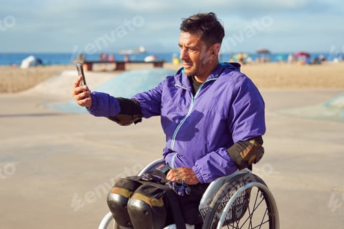 Preview: disabled athlete man in wheelchair taking a selfie with a smartphone