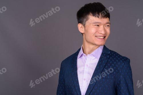 Preview: Portrait of young Chinese businessman against gray background