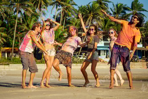 Preview: multinational multicultural mixed race friends in holi dust on beach in Goa