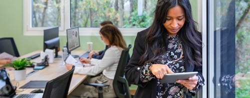 Preview: Banner of concentrated hispanic woman working with a tablet against an office window