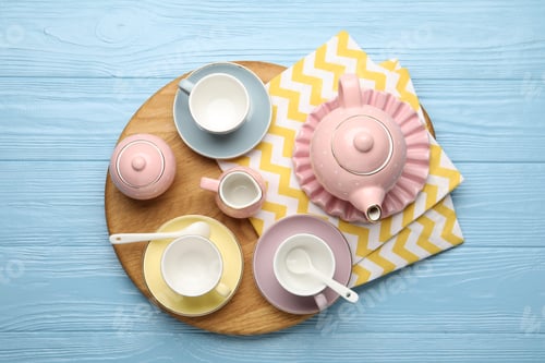 Preview: Beautiful ceramic tea set for children and napkin on light blue wooden table, top view