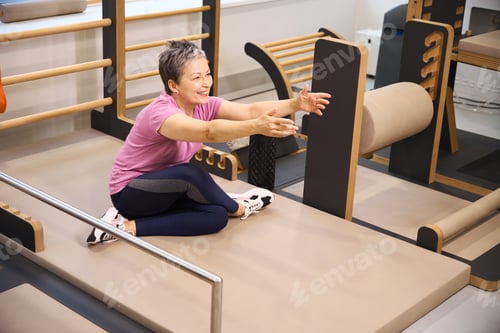 Preview: Smiling woman stretching after injury during recovery in rehabilitation gym
