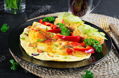 Aperçu: Omelette with paprika, cheese and tomatoes with sandwiches on black plate.