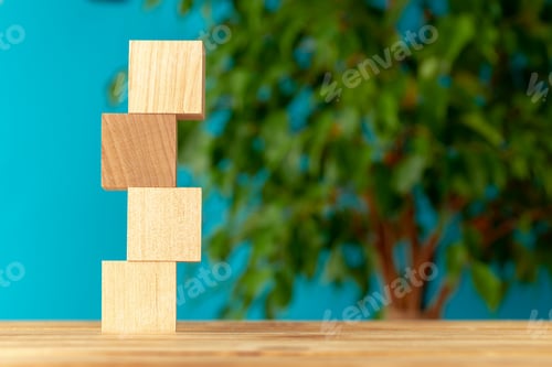 Preview: Wooden blocks on desk against blurred plant background