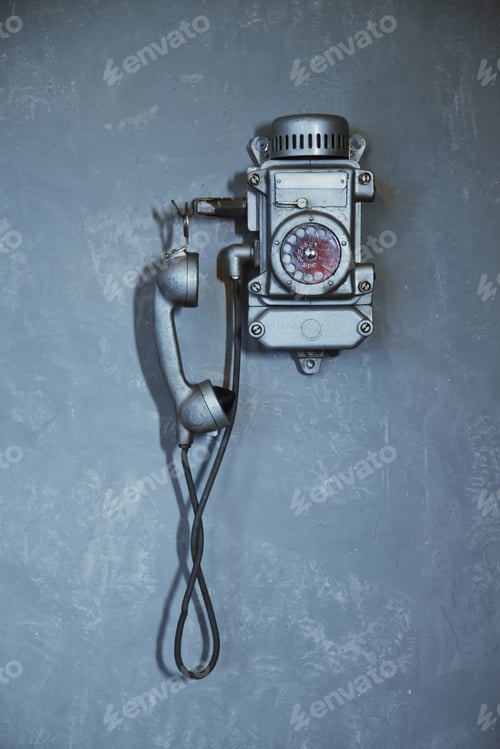 Preview: Old vintage wired telephone for communication hangs on textured gray wall
