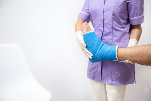 Preview: Female doctor in a blue medical gown checking broken leg on male patient.
