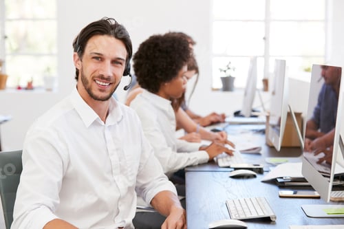 Preview: Hispanic man with headset on smiling to camera in an office