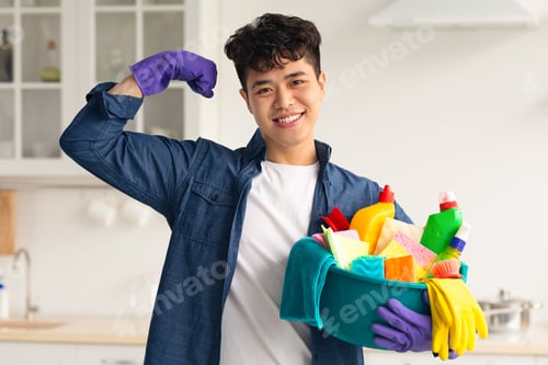 Preview: Positive asian guy with cleaning supplies showing muscles