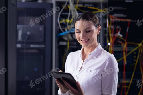 Preview: Caucasian female engineer smiling while using digital tablet in computer server room