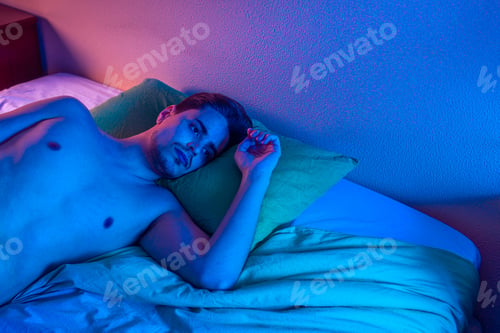 Preview: young man with insomnia trying to sleep at night