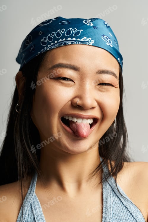 Preview: Joyful expression of a young beautiful Asian woman with a playful spirit in a studio setting