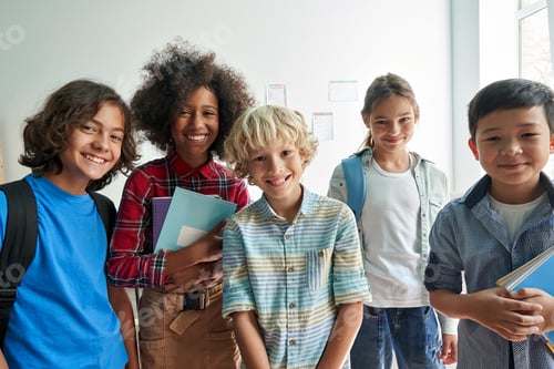 Preview: Happy diverse junior school students children looking at camera in classroom.