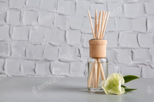 Preview: Aromatic reed freshener and flower on table against textured wall, space for text