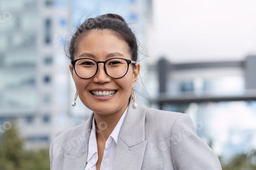 Preview: Young cheerful businesswoman in eyeglasses and grey suit