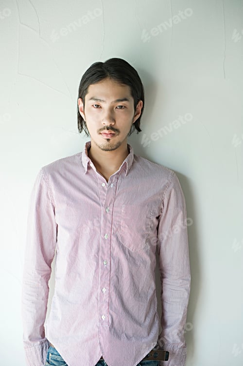 Preview: Serene young man leaning against a white wall
