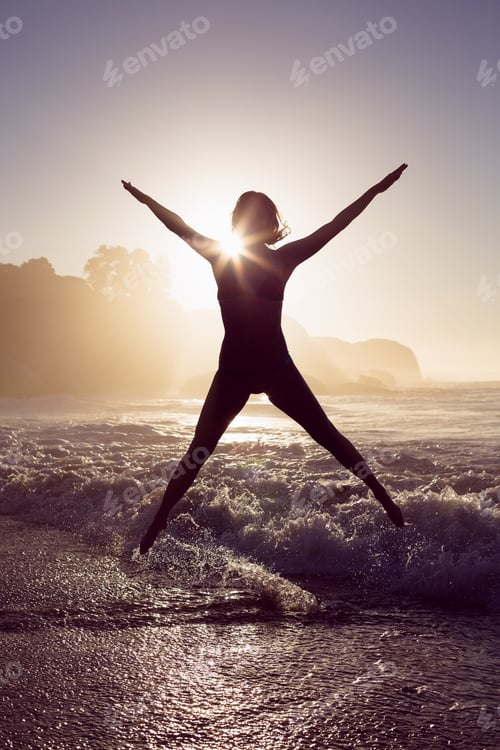 Preview: Happy blonde in the sea leaping in bikini on a sunny day