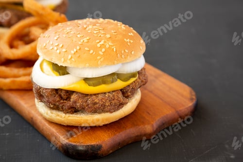 Preview: Homemade Mississippi Slug Burgers with onion rings on a rustic wooden board on a black background
