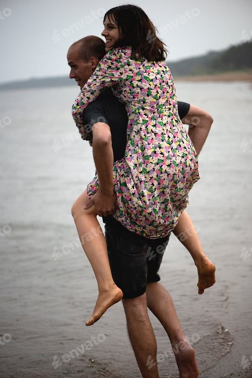 Preview: Young attractive couple having fun on the beach,rainy summer day,bare foot