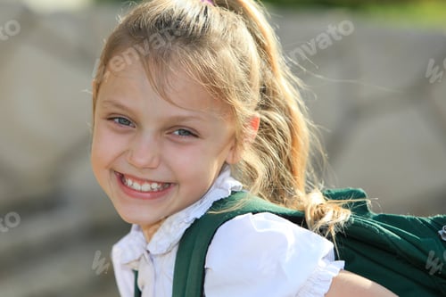 Visualização: Menina sorridente do ensino fundamental com mochila nas escadas ao ar livre