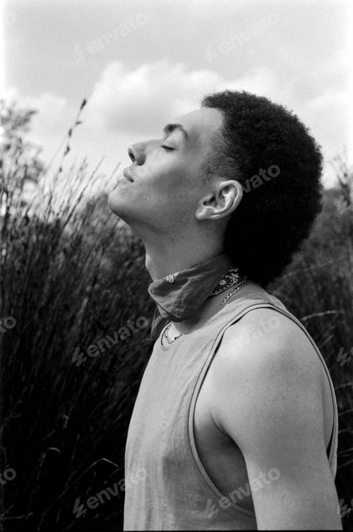 Preview: Young man breathing fresh air in nature, wearing tank top and bandana