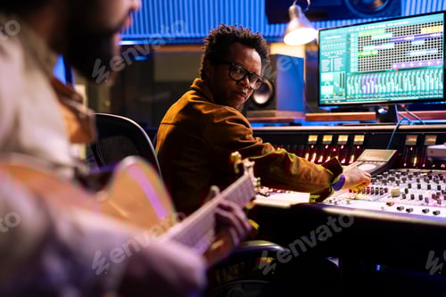 Preview: Musician composing a new record with his guitar and mixing console in studio