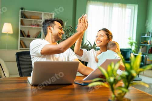 Preview: Father celebrates success working on laptop while mother joins him carrying newborn baby boy indoors