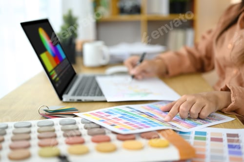 Preview: Close up of interior designer reviewing color swatches and design layouts on her desk
