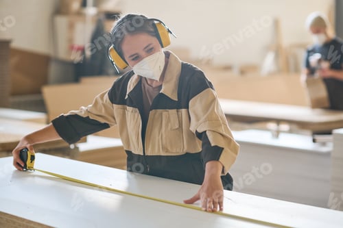 Preview: Woman making measurement of board