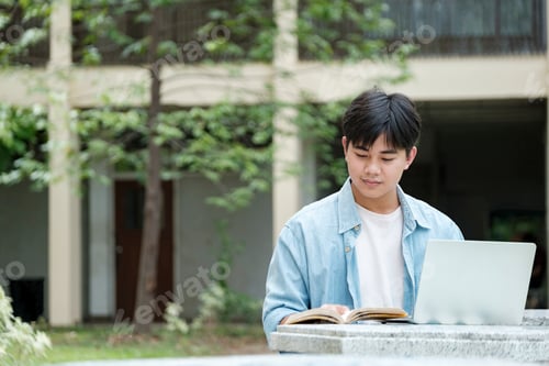 Preview: Young Man Studying with Laptop and Book Outdoors