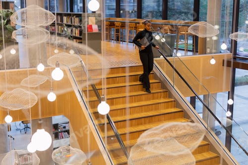 Preview: Student descending staircase in library