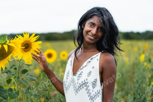 Preview: Smiling Indian woman in field with blooming sunflowers