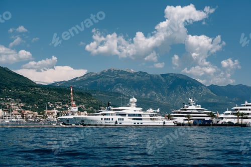 Preview: Luxurious white superyachts stand at Porto marina with mountains in the background