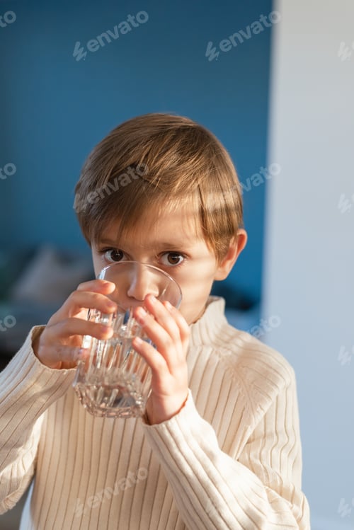 Preview: A child drinks water from a glass in the living room.