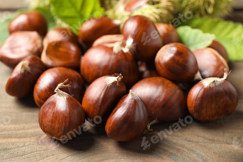 Preview: Fresh sweet edible chestnuts on wooden table, closeup