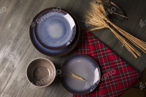 Preview: High angle shot of blue plates, a bowl and wheat on the table