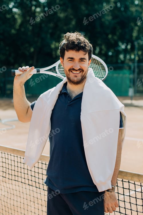 Preview: Young man smiling, holding tennis racket on court