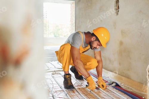 Preview: Almost done. Worker in yellow colored uniform installing underfloor heating system