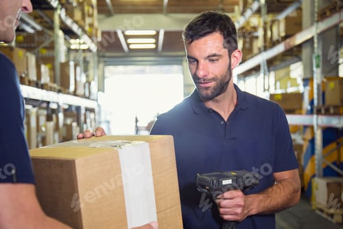 Preview: Warehouse worker using barcode scanner on cardboard box in distribution warehouse