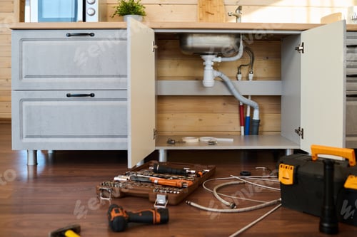 Preview: Open cabinet of kitchen counter with metallic sink and plastic pipes inside